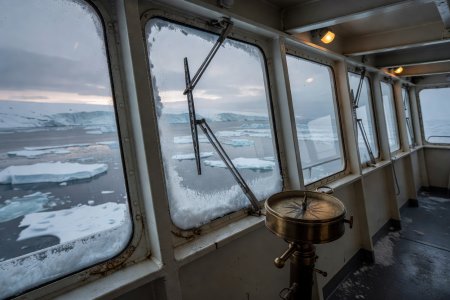 Enclosed polar ship bridge wing with heated glass panes, pantograph wipers, and manual azimuth repeater